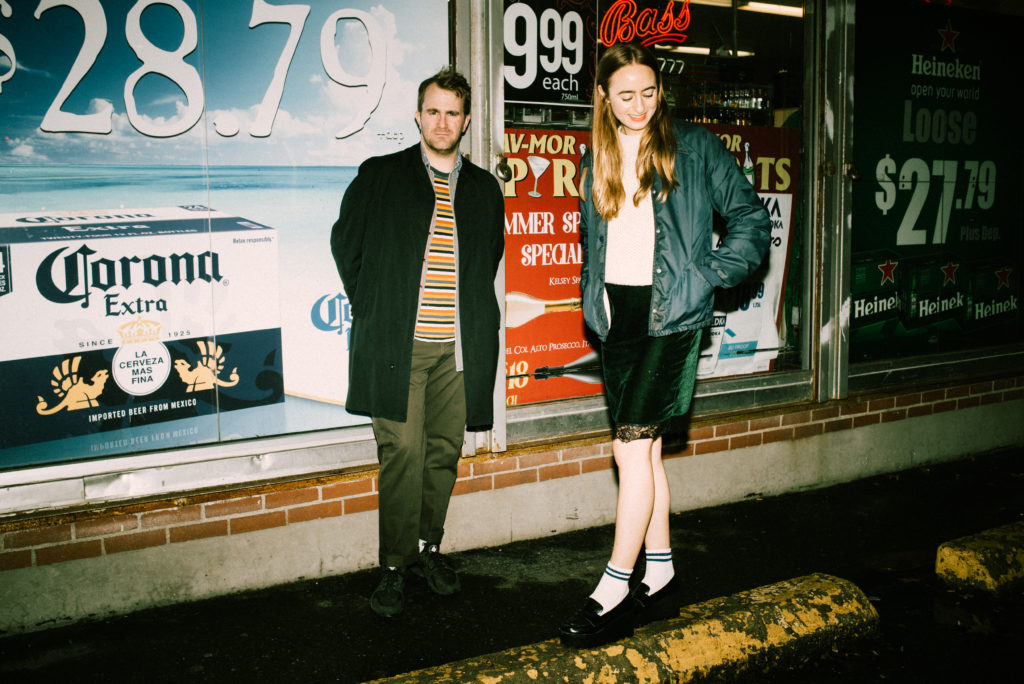 a couple hanging out at night in front of a liquor store