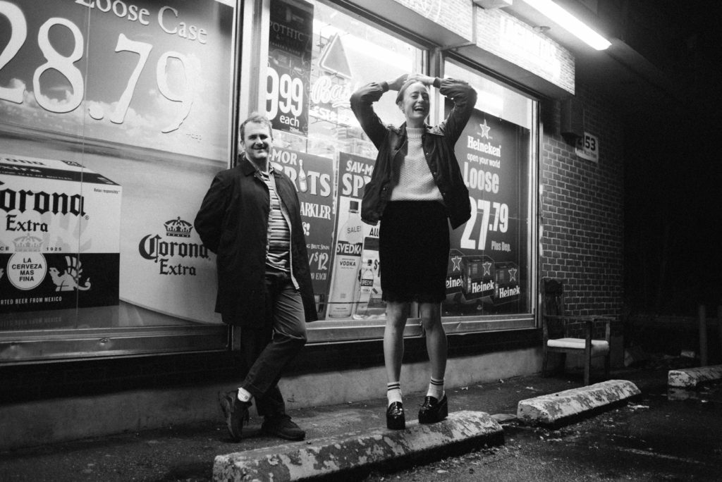 a couple hanging out at night in front of a liquor store