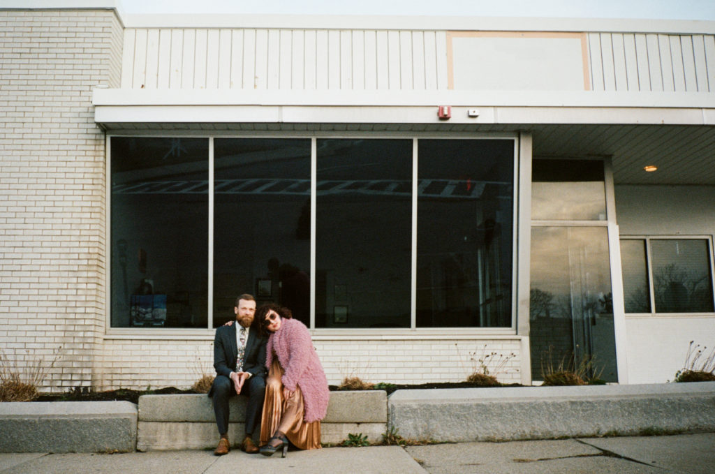 a couple sitting on the curb in front of a building