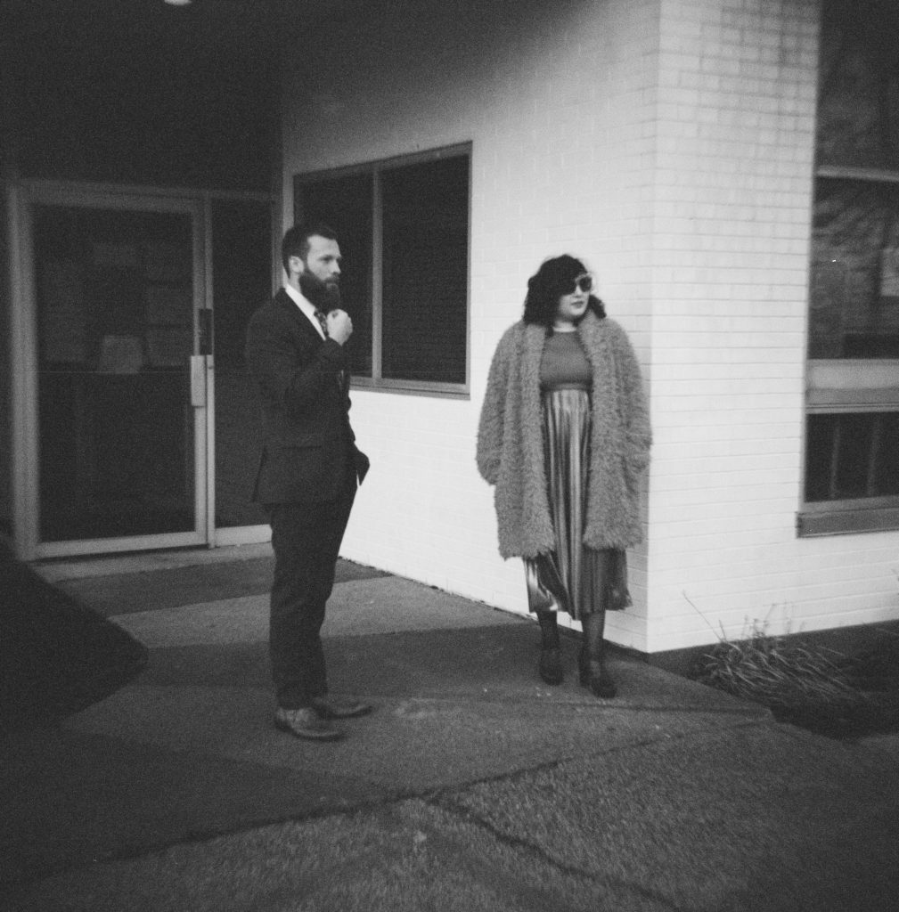 a couple standing in front of a building looking into the distance