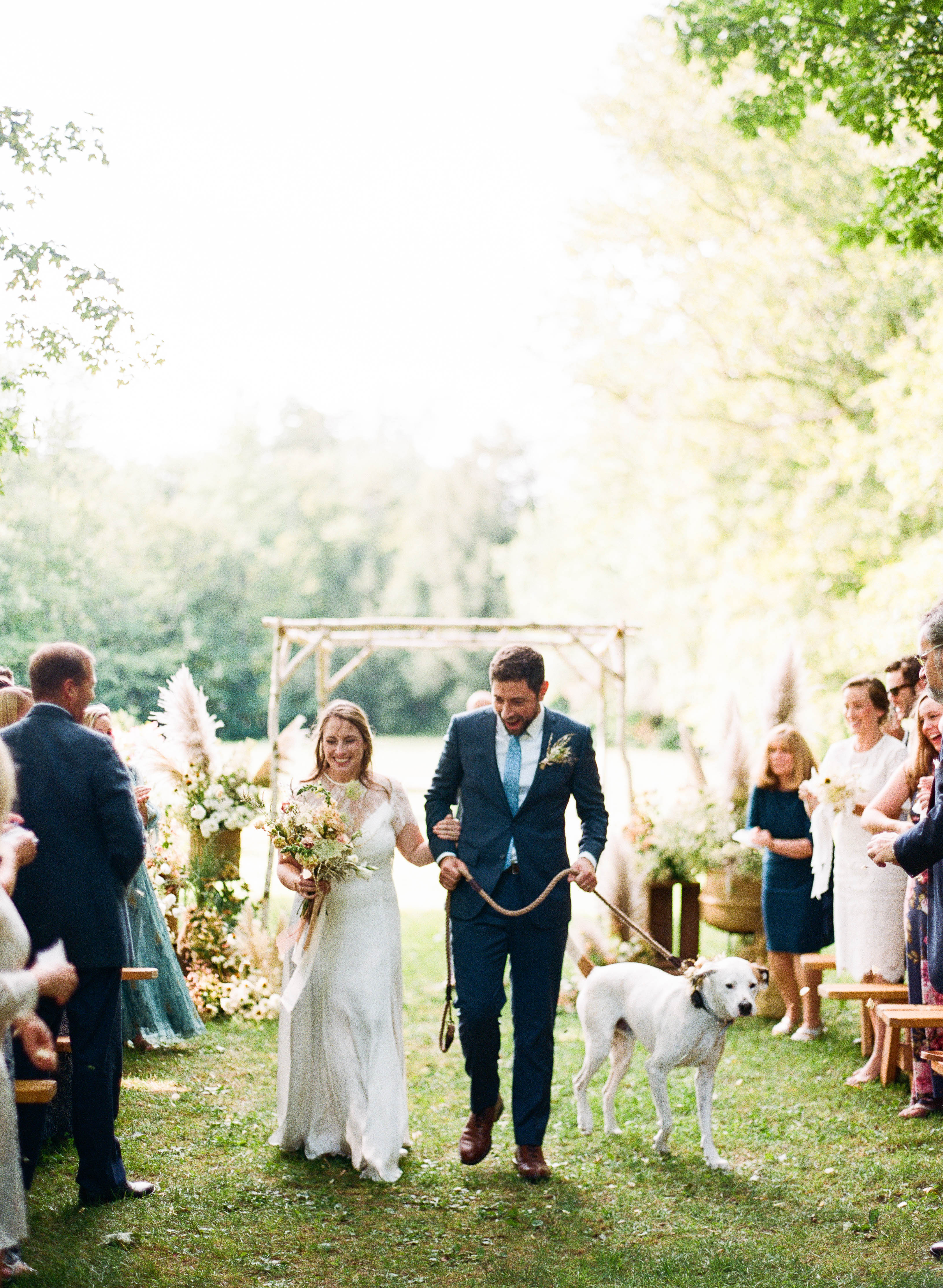 the bride and groom walking down the aisle with their dog at the end of their ceremony